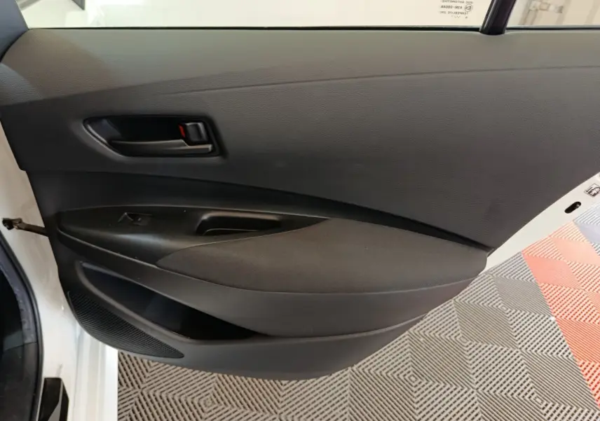 Vue intérieure de la porte arrière gauche noire de la Toyota Corolla Hybride 122h Active blanche de 2020.