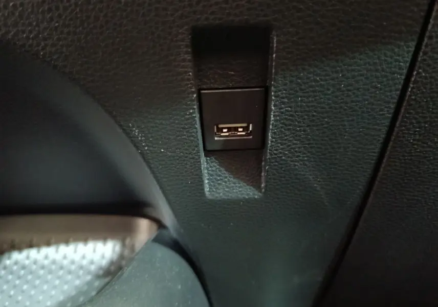 Prise USB noire intégrée dans la console intérieure d'une Toyota Corolla Hybride blanche, vue rapprochée.