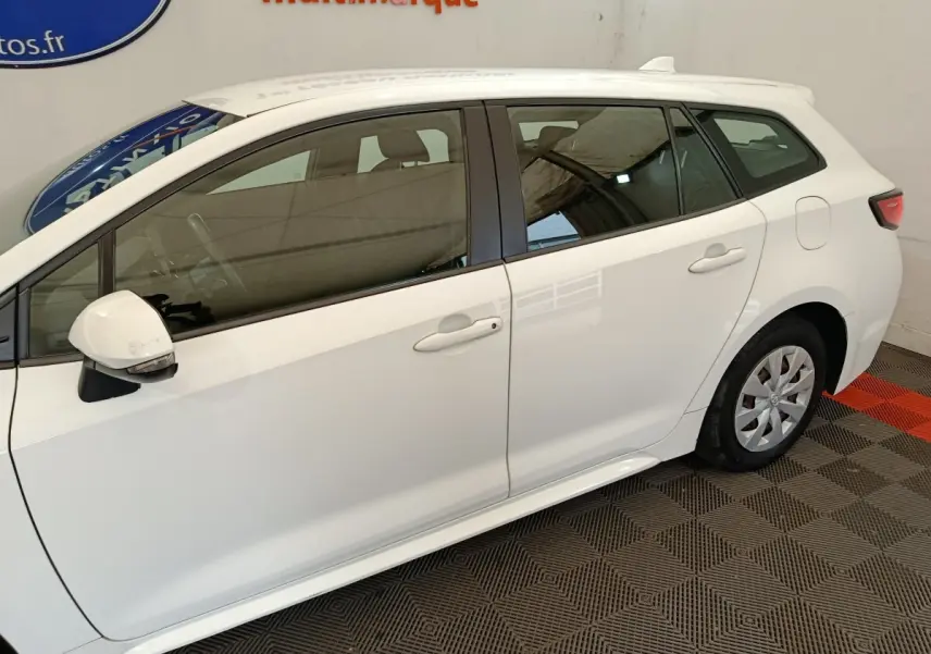 Profil droit d'une Toyota Corolla Hybride 122h Active blanche, avec rétroviseur blanc et jantes acier visibles.