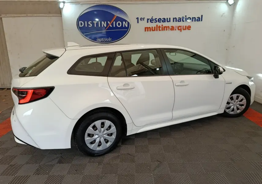 Vue de profil côté droit d'une Toyota Corolla Hybride 122h Active blanche en version break, avec jantes acier et feux arrière LED.
