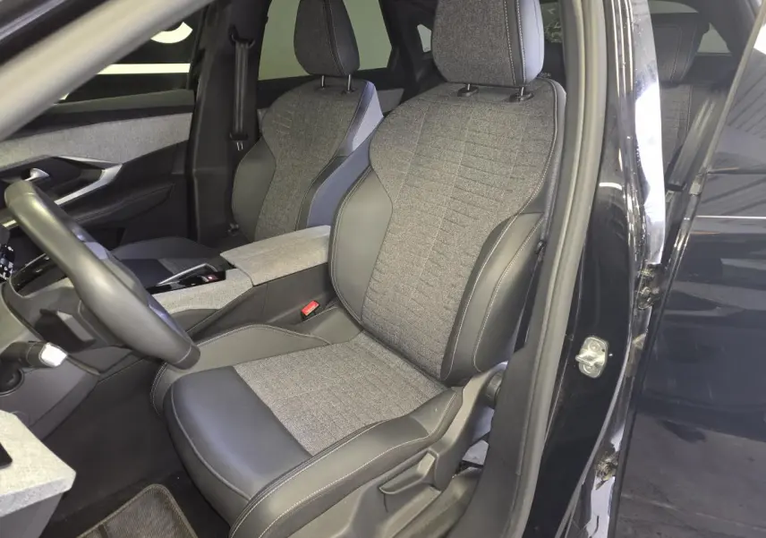 Vue intérieure côté conducteur du Peugeot 3008 noir 2025, sièges tissu gris et cuir noir avec console centrale assortie.
