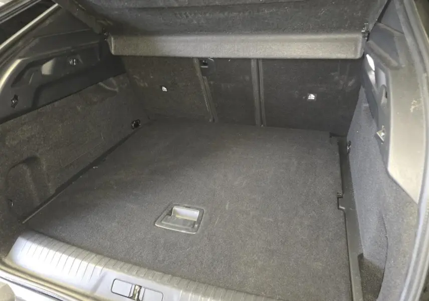 Coffre spacieux noir du Peugeot 3008 1.2i Hybrid 2025 vu de l'arrière avec plancher plat et habillage tissu.