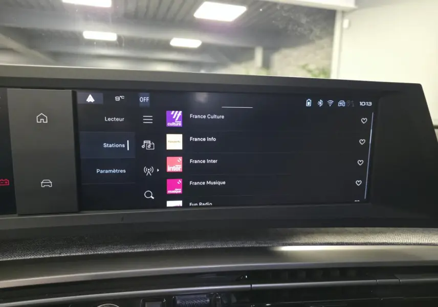 Écran tactile central du Peugeot 3008 noir hybride 2025 affichant les stations radio dans un intérieur moderne.