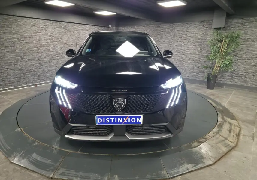 Vue avant d'un Peugeot 3008 noir 2025 avec feux LED à 3 griffes et calandre noire laquée dans un showroom.