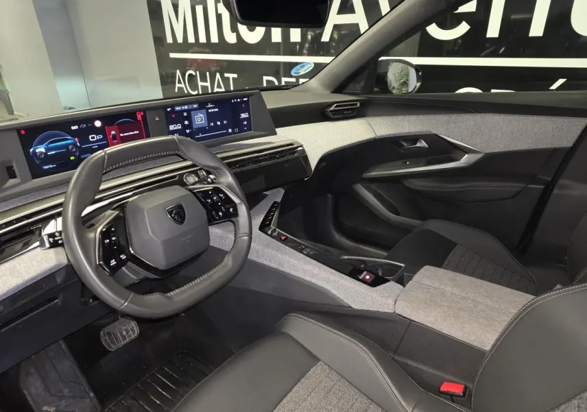 Intérieur du Peugeot 3008 noir hybride, vue côté conducteur, tableau de bord numérique et sellerie tissu gris et noir.