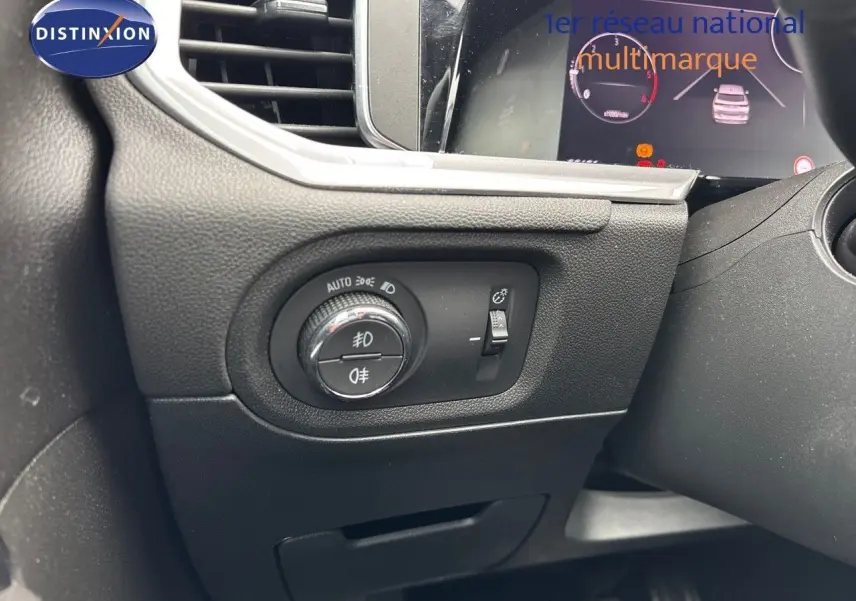 Gros plan sur le tableau de bord à gauche du volant de l'Opel Grandland 2023, avec commandes d'éclairage et réglage de phares.