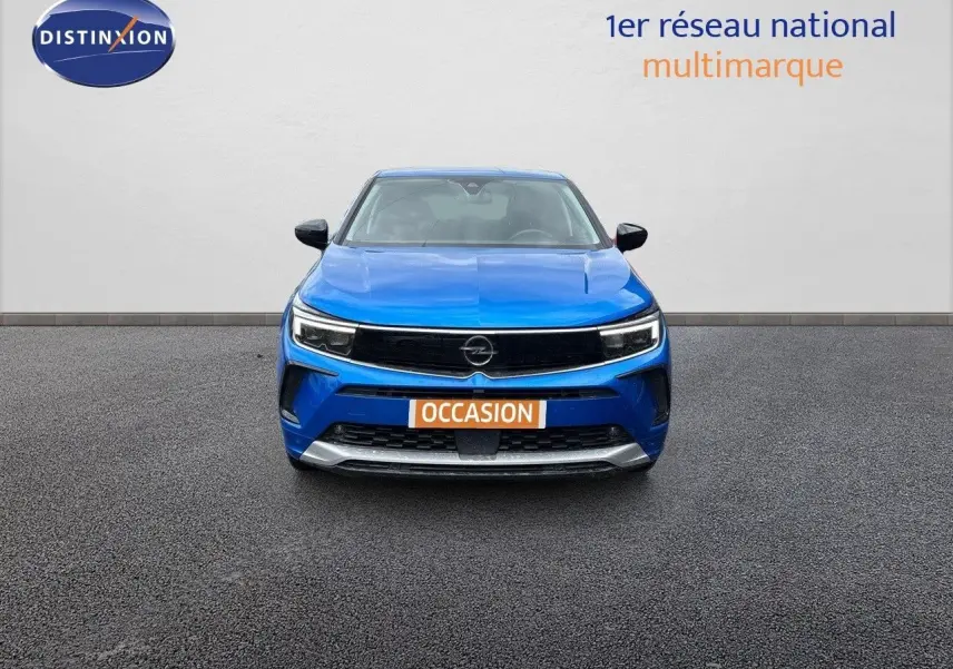 Vue frontale d'un Opel Grandland bleu Spektrum Metal avec plaque "OCCASION" sur un sol gris.