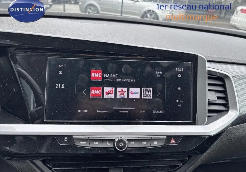 Tableau de bord de l'Opel Grandland 2023 avec écran tactile affichant stations radio, ambiance intérieure noire moderne.