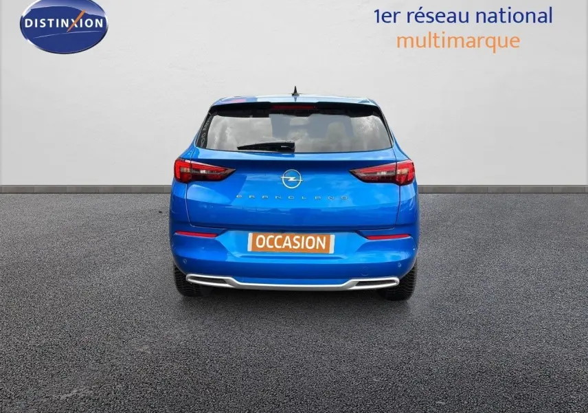 Vue arrière d'un Opel Grandland bleu Spektrum Metal avec plaque "OCCASION" sur fond neutre.