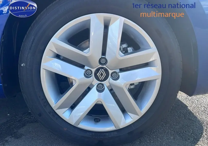 Gros plan sur la jante alliage argentée de la Renault Clio V bleu iron, avec logo Renault au centre.