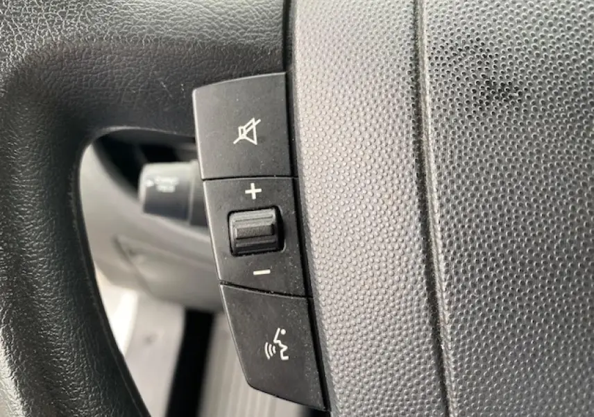 Gros plan sur les commandes audio et vocales au volant noir du fourgon blanc Opel Movano 2023.