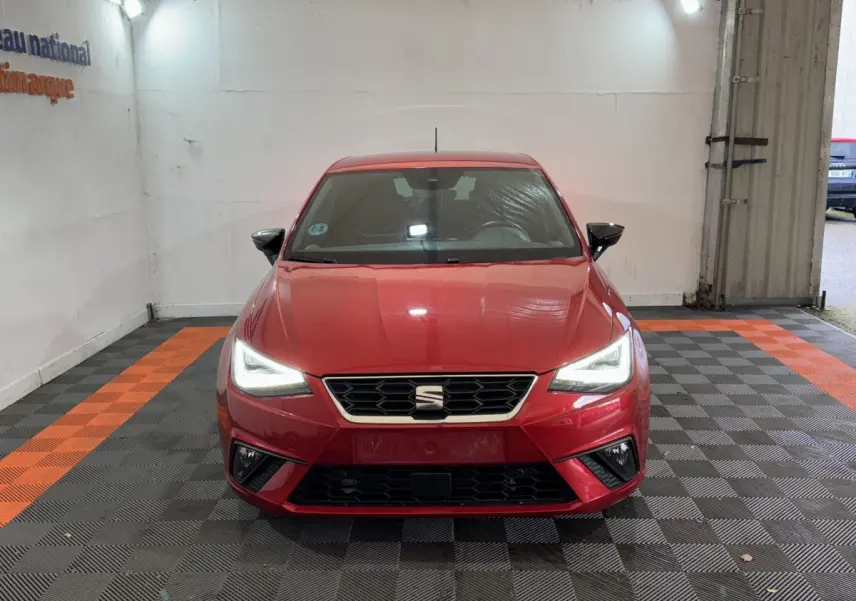 Vue frontale d'une SEAT Ibiza rouge 2024 avec phares LED allumés dans un garage éclairé.