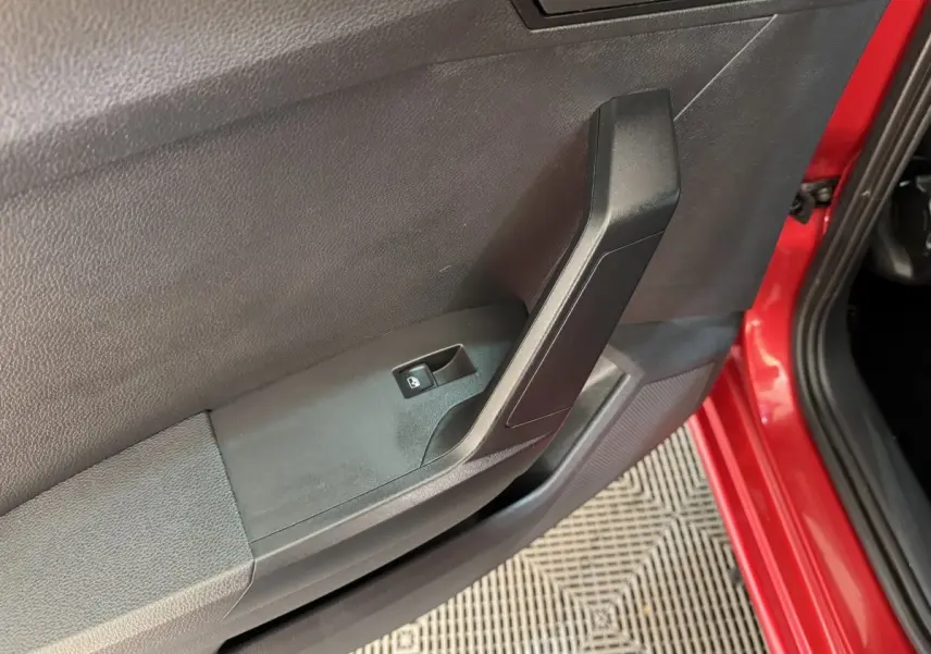Gros plan sur la porte avant gauche rouge d'une SEAT Ibiza 1.0 TSI 110 FR avec bouton de verrouillage centralisé.