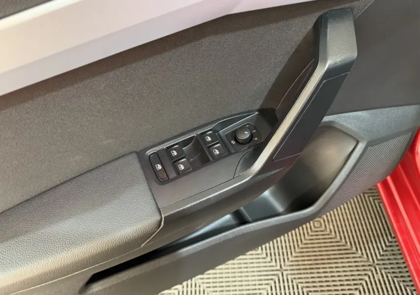 Gros plan sur la porte côté conducteur de la SEAT Ibiza rouge 2024, avec commandes des vitres et rétroviseurs.