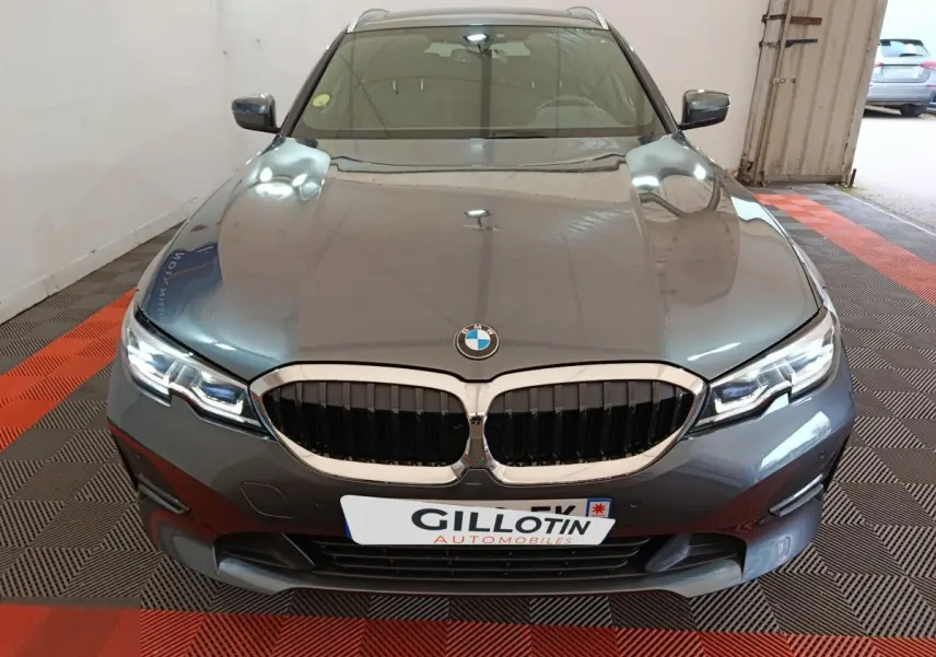 Vue avant d'une BMW Série 3 318d gris clair avec calandre double haricot et phares LED allumés.