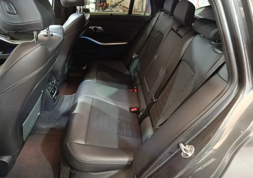Vue intérieure côté droit des sièges arrière en cuir noir de la BMW Série 3 318d Lounge 2022 avec finitions soignées.