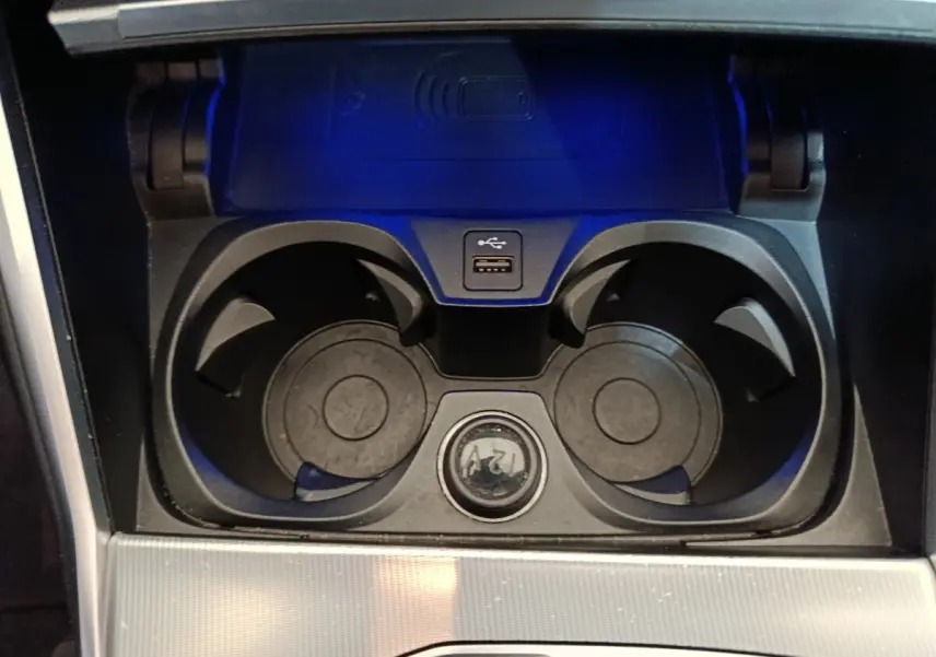 Vue rapprochée de la console centrale noire de la BMW Série 3 318d avec porte-gobelets, prise USB et prise 12V.