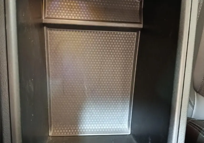 Gros plan sur le compartiment de rangement central noir avec port USB et recharge sans fil dans une BMW Série 3 gris clair.