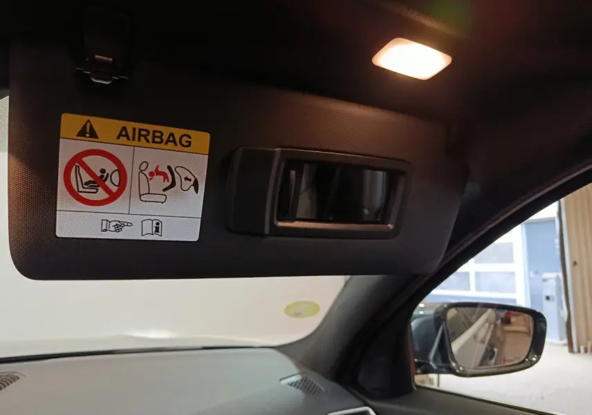 Détail du pare-soleil côté conducteur avec miroir intégré et avertissement airbag dans une BMW Série 3 grise.