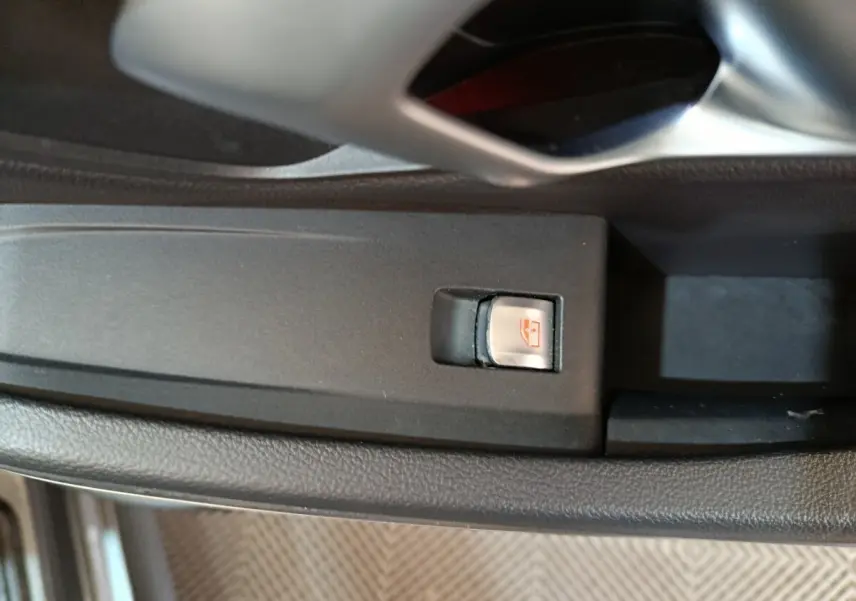 Gros plan sur le bouton de commande de lève-vitre côté conducteur dans une BMW Série 3 gris clair, intérieur noir.