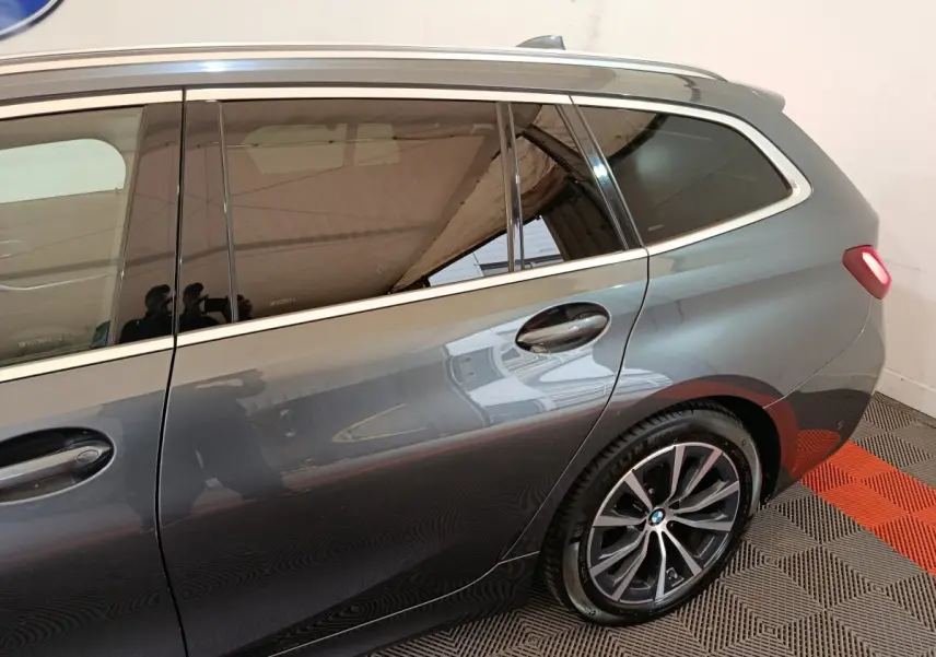 Vue latérale droite sur la partie arrière d'une BMW Série 3 Touring gris clair avec jante alliage et vitre teintée.