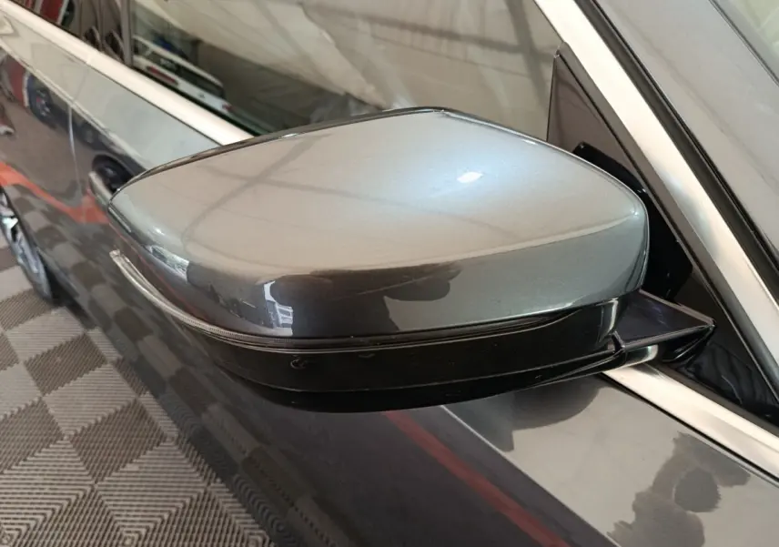 Rétroviseur droit gris clair de BMW Série 3 318d 2022, vue rapprochée avec carrosserie brillante et cadre chromé.