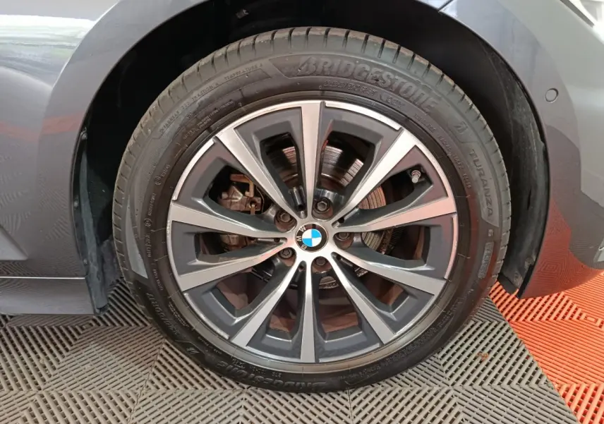 Gros plan sur la roue avant droite gris clair d'une BMW Série 3 318d avec jante alliage et logo BMW au centre.