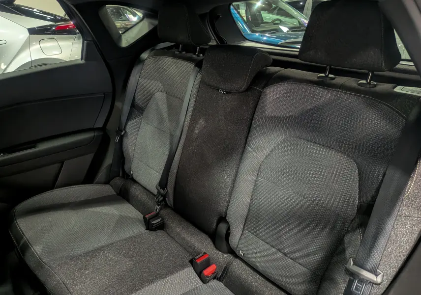 Vue intérieure sur les sièges arrière en tissu gris du Renault Captur 2025, avec ceintures de sécurité et appuie-têtes visibles.