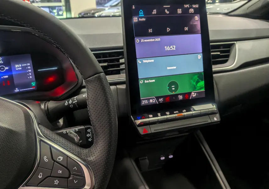 Vue rapprochée de l'intérieur du Renault Captur 2025 montrant le volant multifonction et l'écran tactile central vertical.