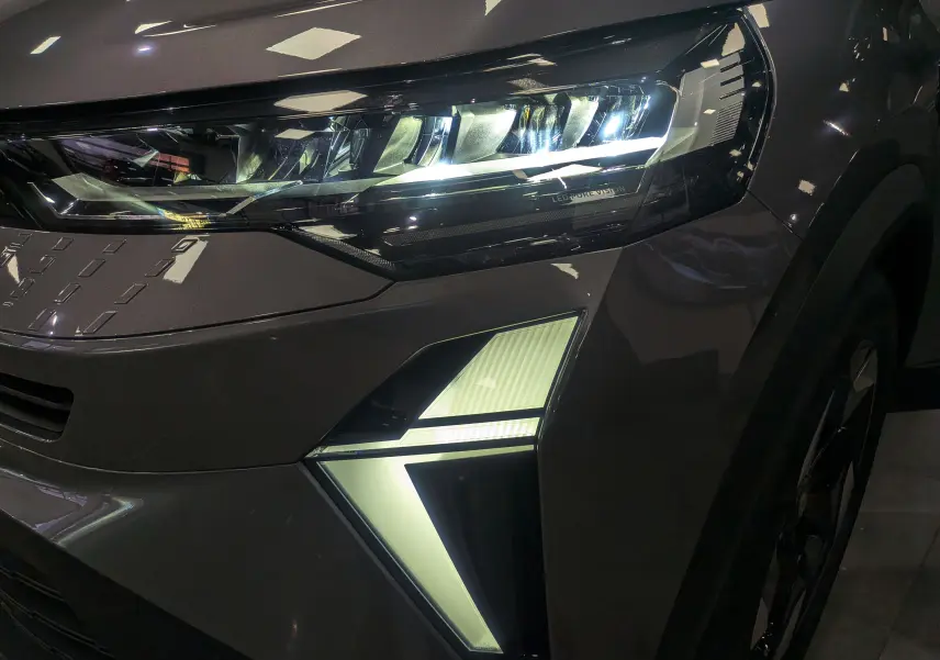 Gros plan sur le phare avant droit du Renault Captur Gris Cassiopé 2025 avec éclairage LED distinctif en forme de flèche.