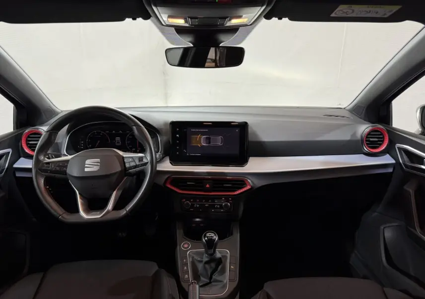 Vue frontale de l'habitacle noir de la SEAT Ibiza 1.0 TSI 110 FR 2024 avec volant cuir alu et écran tactile central.