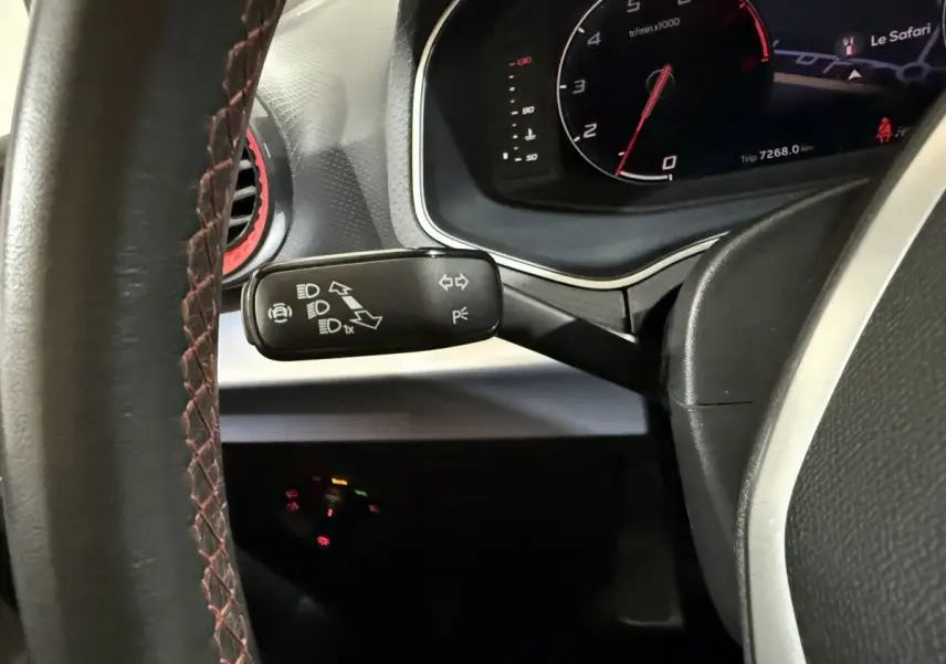 Gros plan sur le commodo gauche du volant cuir alu de la SEAT IBIZA 1.0 TSI 110 FR noir, avec tableau de bord numérique visible.