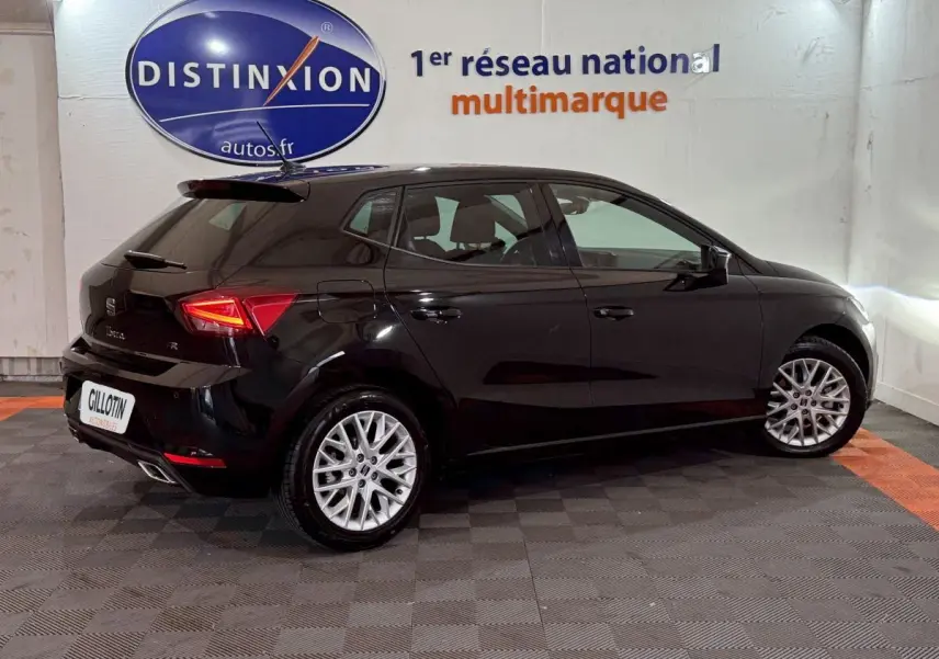 Vue côté droit arrière d'une SEAT Ibiza 1.0 TSI 110 FR noire avec jantes alliage et feux LED distinctifs.