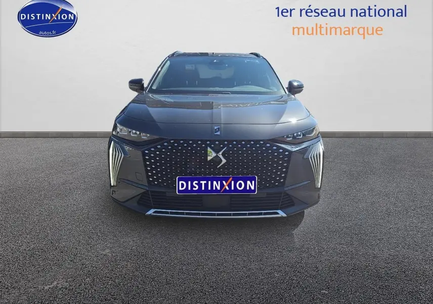 Vue frontale d'un DS7 gris titane 2025 avec calandre DS Pixel LED et feux verticaux distinctifs allumés.