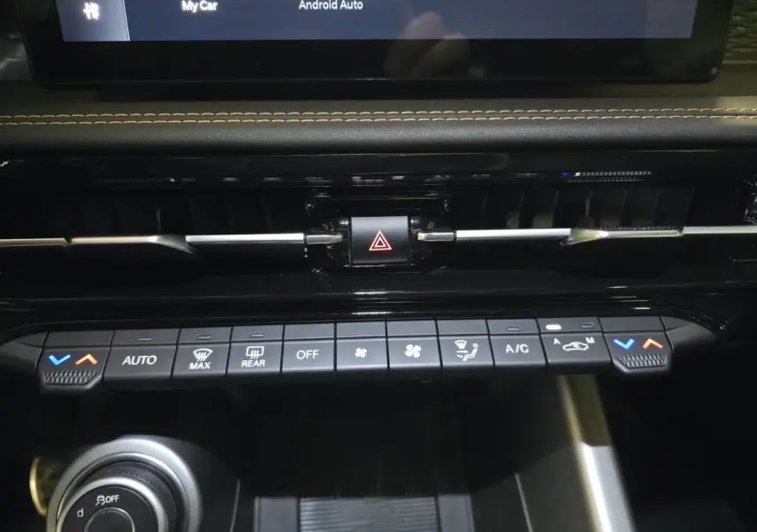 Vue rapprochée de la console centrale noire de l'Alfa Romeo Tonale 2025 avec commandes climatisation et bouton hazard.