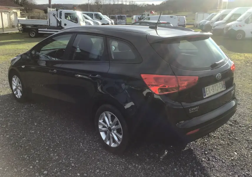KIA CEE'D SW noire vue 3/4 arrière droit, break diesel avec jantes alliage et feux arrière allumés.
