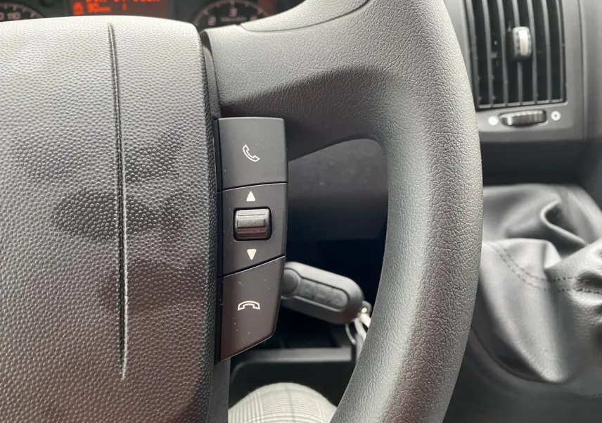 Gros plan sur le volant noir de l'Opel Movano Fourgon 2022 avec commandes d'appel et levier de vitesses visible.