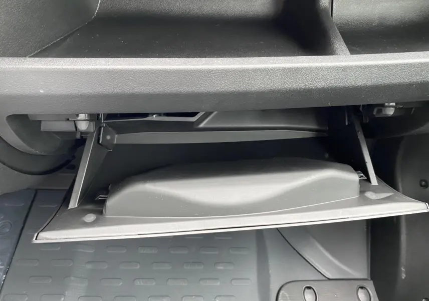 Gros plan sur la boîte à gants ouverte de l'Opel Movano Fourgon blanc, intérieur noir et plancher caoutchouc.