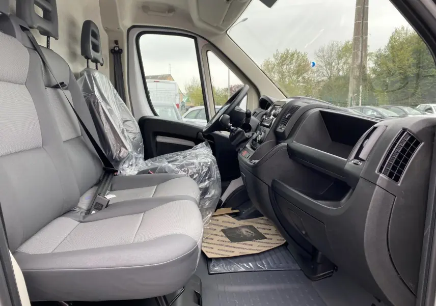 Intérieur côté droit de l'Opel Movano Fourgon blanc 2022, montrant les sièges gris et le tableau de bord noir.