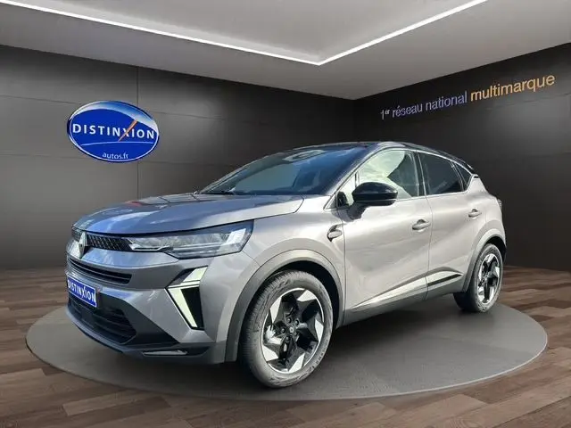 Vue 3/4 avant d'un Renault Captur 2025 gris Cassiopée avec toit noir et jantes distinctives en concession.