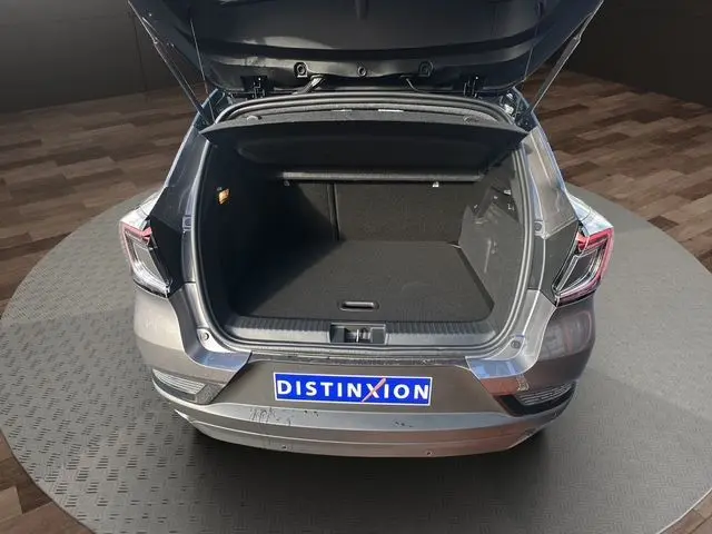 Vue arrière ouverte du Renault Captur 2025 gris Cassiopée avec toit noir, montrant le coffre spacieux et la plaque Distinxion.