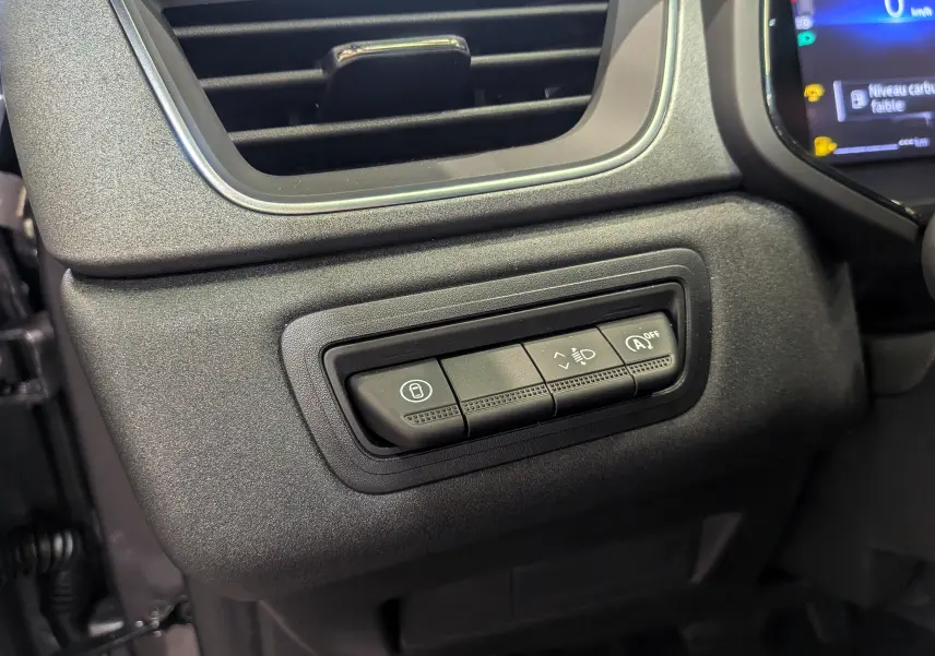 Gros plan sur les commandes de réglage des feux et fonction start/stop du tableau de bord du Renault Captur gris Cassiopé 2025.