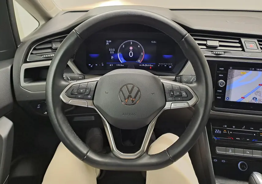 Vue intérieure centrée sur le volant noir du Volkswagen Touran 2024 avec tableau de bord numérique et écran tactile.
