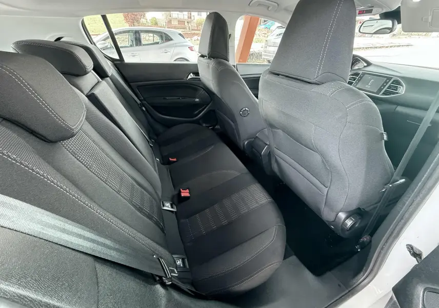 Vue intérieure côté droit montrant les sièges arrière noirs en tissu d'une Peugeot 308 blanche.
