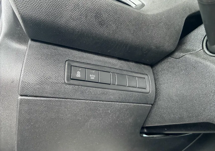 Gros plan sur les boutons de contrôle du tableau de bord côté gauche d’une Peugeot 308 blanche, version 2016.