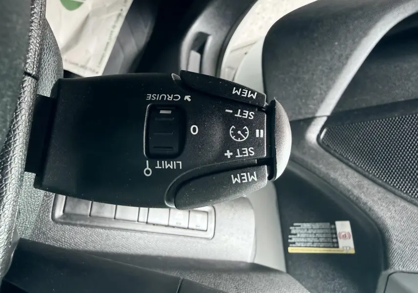Gros plan sur la commande de régulateur de vitesse noire dans l’habitacle d’une Peugeot 308 blanche de 2016.