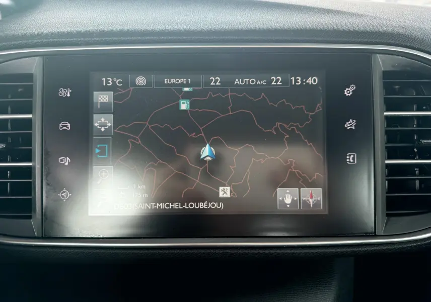 Écran tactile central du tableau de bord avec navigation GPS affichée dans une Peugeot 308 blanche.