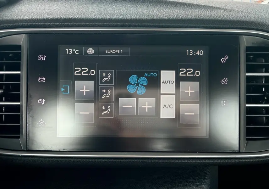 Écran tactile central de la Peugeot 308 blanc nacré, affichant la climatisation réglée à 22°C en mode automatique.