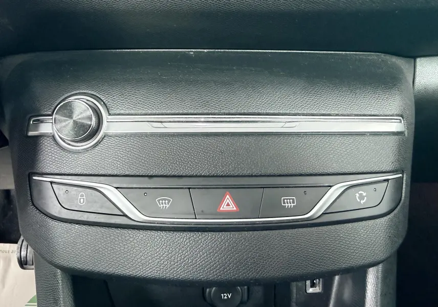 Gros plan sur la console centrale noire de la Peugeot 308 avec boutons de verrouillage, dégivrage et alerte.