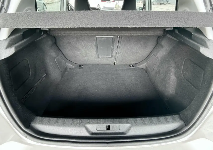 Coffre ouvert vu de l'arrière d'une Peugeot 308 blanche, montrant un espace de chargement vide et propre.